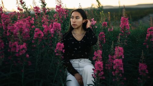 Beautiful young woman standing by flowering plants