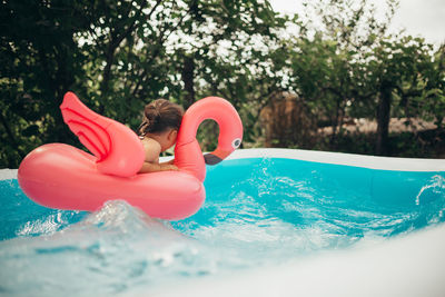 Little playing in the pool with flamingo water toy.