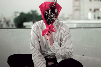 Close-up of man covering face with bouquet
