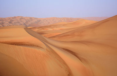 Scenic view of sand dunes in desert against clear sky