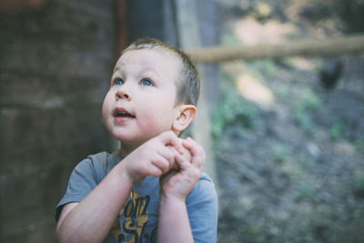 Thoughtful boy holding egg while standing outdoors