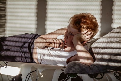 Sunlight falling on thoughtful boy lying on bed