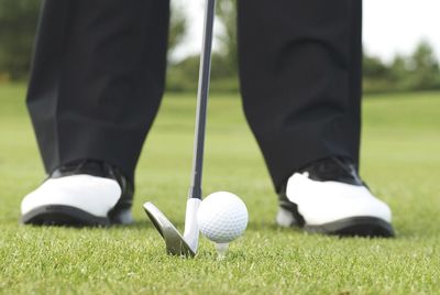 Low section of man standing at golf course