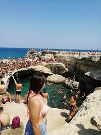 Rear view of people on beach against clear sky