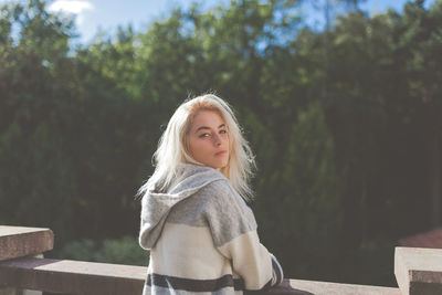 Portrait of young woman against trees