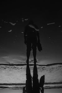Low section of silhouette woman standing at beach