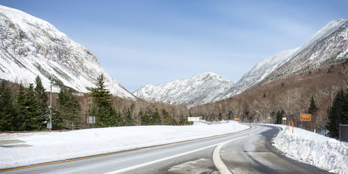 Road by snow covered mountain against sky