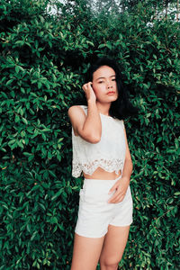 Portrait of beautiful woman standing against plants
