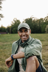 Portrait of happy man wearing cap while sitting in playground