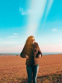 Woman wearing sunglasses while standing on grass against sky