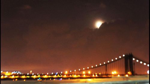 Illuminated bridge over river at night