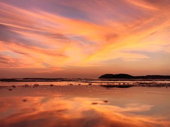 Scenic view of sea against dramatic sky during sunset