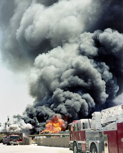 Fire engines against smoke emitting from burning crates in factory