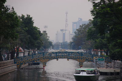 Bridge over river in city against sky