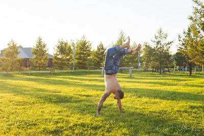 Full length of man jumping on field against sky