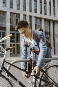 Businessman locking bicycle at parking station in city