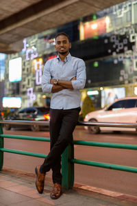 Full length portrait of young man standing on illuminated bus