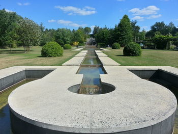 Fountain and trees at park against sky