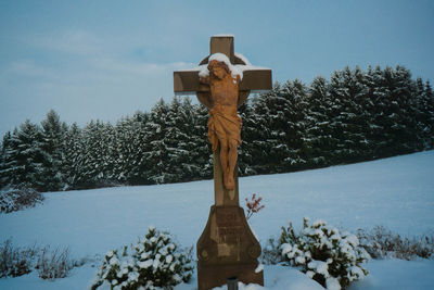 Low angle view of cross statue against trees