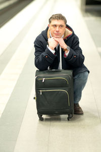 Man with luggage sitting at railroad station platform