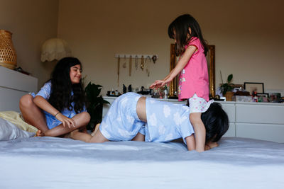 Children playing in the bedroom of parents on big bed