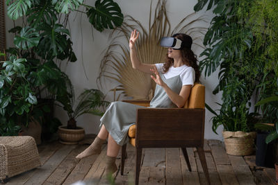 Excited woman designer or florist enjoy using virtual reality goggles for work at indoors garden