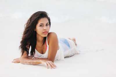Portrait of young woman lying on beach