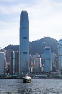 Passenger craft sailing on sea against buildings