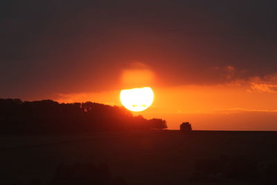 Scenic view of silhouette landscape against orange sky