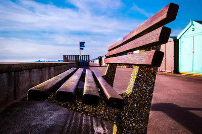 Close-up of empty bench on promenade against sky