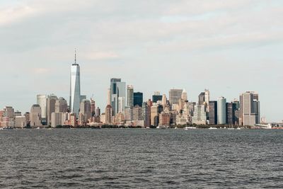 Sea by modern buildings against sky in city