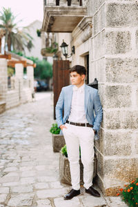 Young man standing on footpath by building