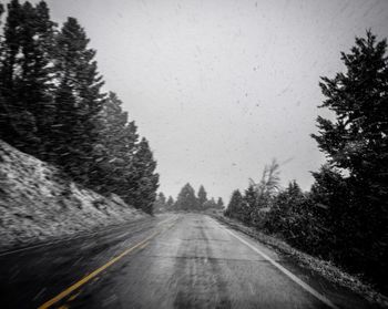 Road amidst trees against clear sky