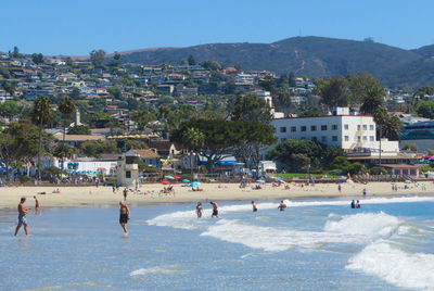 People at beach against clear blue sky