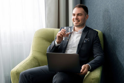 Businessman drinking water while sitting in chair