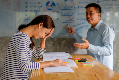 Friends studying with school supplies on table at home