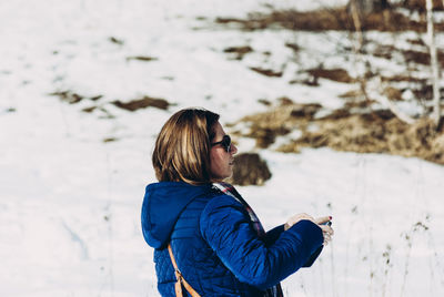Side view of mature woman standing on snow covered field