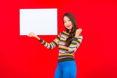 Portrait of a smiling young woman against red background