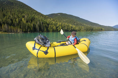 Man rowing boat on lake against mountains