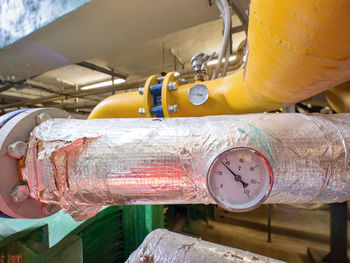 Close up view of industrial thermometer on insulate system pipe in silver foil.