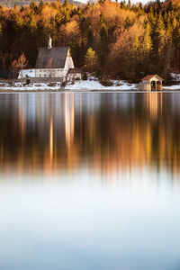 Reflection of trees, church and building in lake