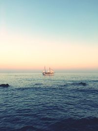 Distant image of ship sailing in sea against sky during sunset