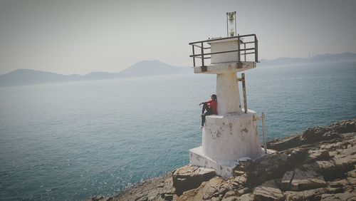 Lighthouse by sea against sky