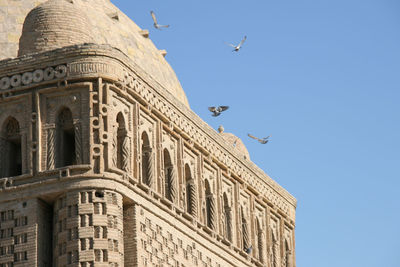 Low angle view of birds flying over po-i-kalyan against clear blue sky