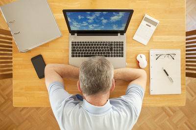 Rear view of man using laptop on table