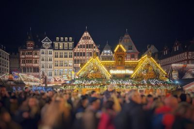 Crowd at illuminated city against sky at night