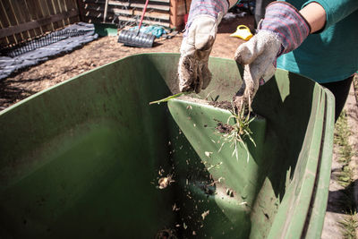 Close up view of hands throwing soil into composting bin