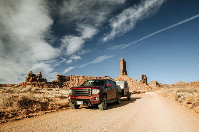 Red truck towing camper along dirt road at valley of the gods, utah