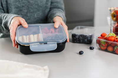 Mother prepares a lunch box with snacks lunch for her school child in the kitchen.