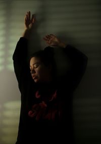 Midsection of woman with arms raised standing at home